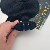 Hand holding the rolled weft of a JAZZWIGS Raw Vietnamese body wave hair bundle in natural black.