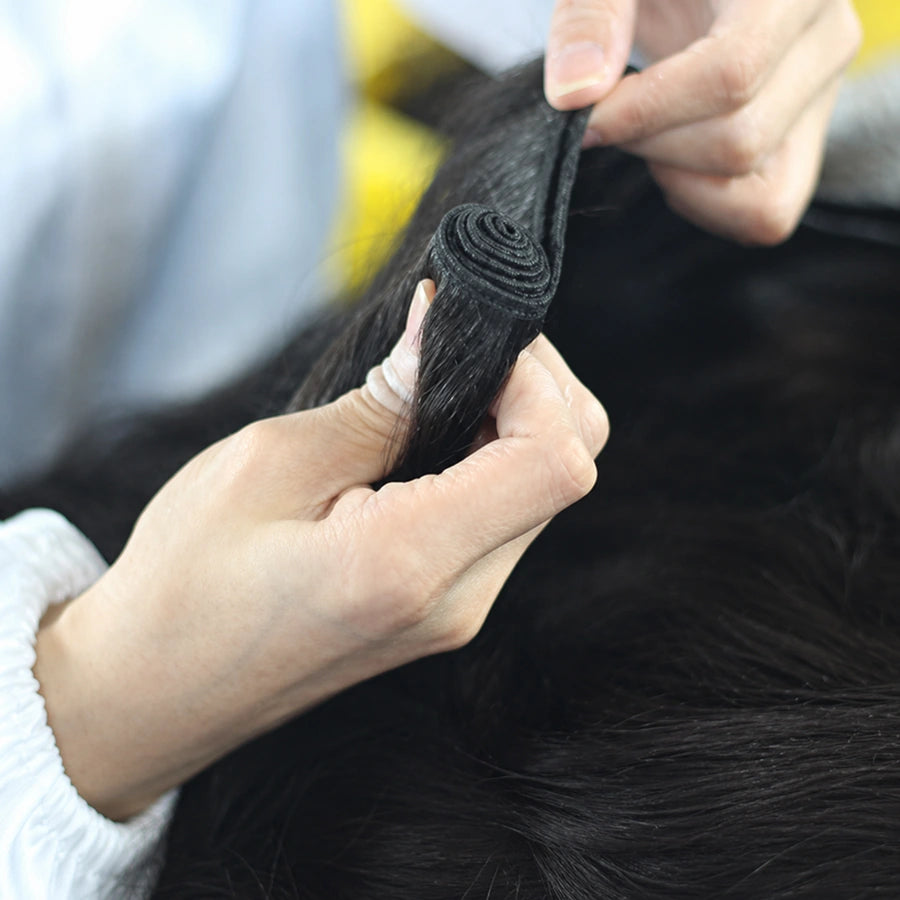 JazzWigs worker inspecting and folding human hair wefts during bundle production