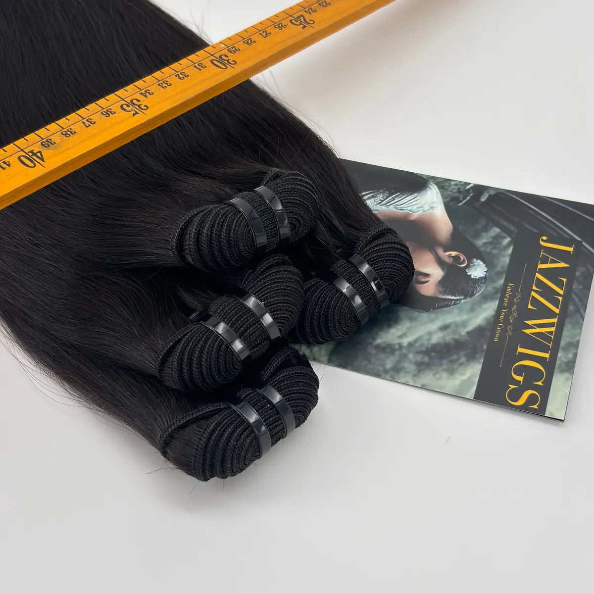 Close-up of JazzWigs Raw Vietnamese Straight Hair 4 Bundle Deal showing bundle wefts, machine-sewn tracks, branded card and measuring ruler.