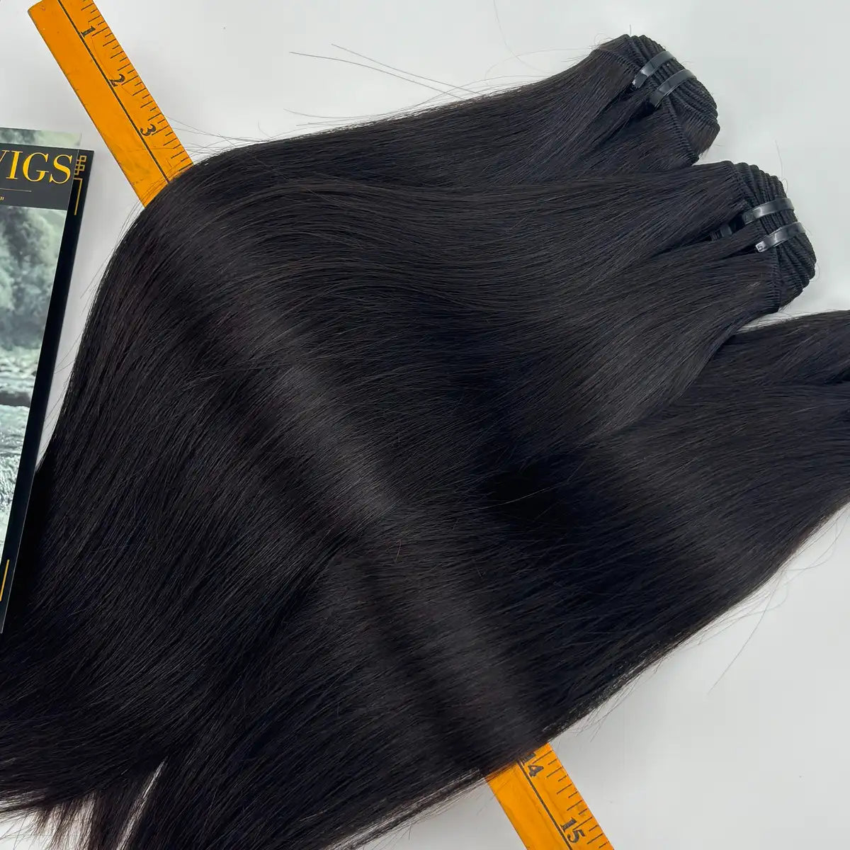 Close-up of JazzWigs Raw Vietnamese Straight Hair in natural black, showing smooth straight texture with measuring ruler.